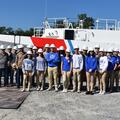 Photo of students at Bollinger with a ship in the background.