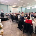 A photo: Chancellor Kristine Strickland speaks on stage during Fletcher Technical Community College’s Chancellor’s Breakfast. Attendees are seated at round tables throughout the room, and a balloon arrangement is positioned to the left of the stage.