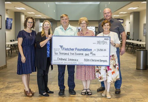 Michael and Christine Pierron Bourgeois stand with Fletcher Technical Community College staff at the Schriever campus while presenting a ceremonial $10,500 check to the Fletcher Foundation to launch their new endowed scholarship. The group smiles while ho