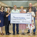 Michael and Christine Pierron Bourgeois stand with �������� staff at the Schriever campus while presenting a ceremonial $10,500 check to the Fletcher Foundation to launch their new endowed scholarship. The group smiles while ho