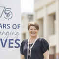 Fletcher Technical Community College Chancellor Dr. Kristine Strickland standing outdoors beside a sign that reads “75 Years of Changing Lives,” with campus buildings in the background.
