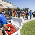 A person serves crawfish from a cooler to a line of students gathered outside on Fletcher Technical Community College’s Schriever Campus during the 2025 Spring Fling event.