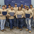 Group photo of Fletcher Technical Community College Line Worker graduates from the 2021 cohort, standing together in front of a Fletcher-branded backdrop and holding their certificates.