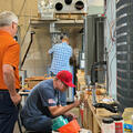 A Fletcher Technical Community College student works on HVAC equipment inside the Air Conditioning and Refrigeration lab while a regional employer observes during the Skilled Trades Recruitment Showcase. Large air conditioning units, tools, and training e
