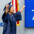 Shirley Billiot, 66, raises her arms in celebration while wearing a cap and gown before receiving her HiSET high school equivalency diploma through Fletcher Technical Community College’s WorkReady U program during a graduation ceremony.