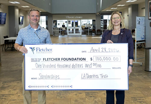 Andy Hughes of Louisiana Charities and Dr. Carrie Cortez of Fletcher Technical Community College stand holding a $100,000 scholarship grant check made payable to the Fletcher Foundation.