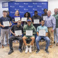 Nine Heavy Equipment Operations graduates pose with their certificates alongside three representatives of Fletcher Technical Community College and Venture Global following the Will to Skill Cohort Four graduation ceremony.