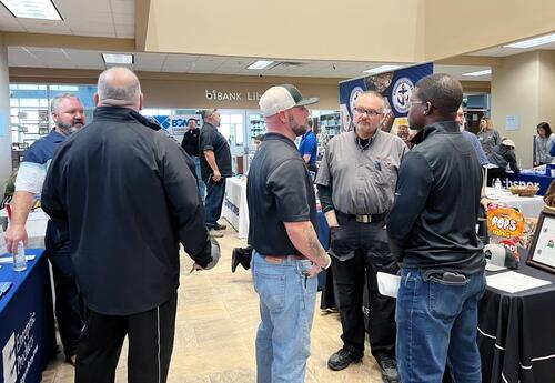 Attendees speak with employer representatives at informational tables during a job fair inside Fletcher Technical Community College.