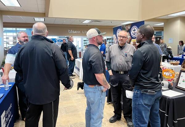 Attendees speak with employer representatives at informational tables during a job fair inside Fletcher Technical Community College.