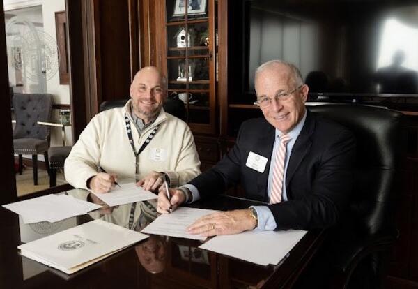 Dr. Angel and Adrian College signing partnership documents