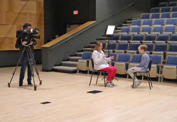 A photo of WMUR News Reporter Kelly O'Brien and a cameraman filming an interview with an Oyster River Middle School 8th grade student.