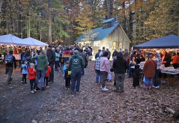 A group of people gathered at night in front of the Moharimet sugar house during the 2025 Pumpkin Stroll.