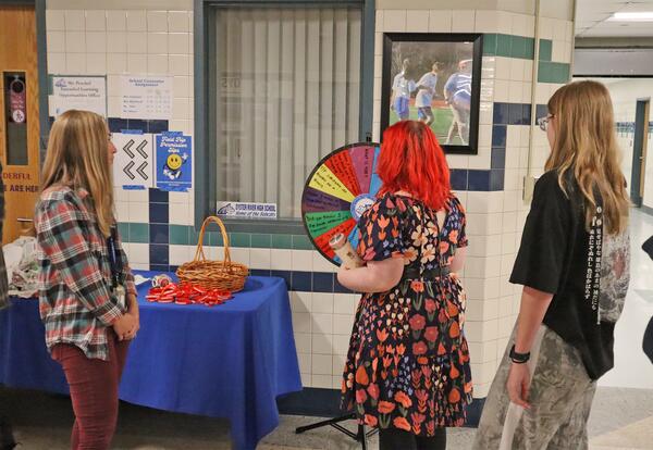 Britta Bartlett is seen with two students spinning the wheel in a Oyster River High School hallway.