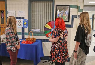 Britta Bartlett is seen with two students spinning the wheel in a Oyster River High School hallway.