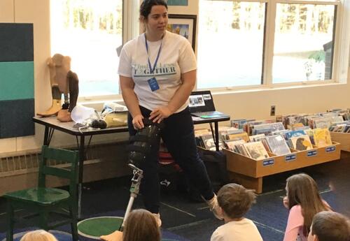 Woman demonstrating the use of a prosthetic leg to a room of students