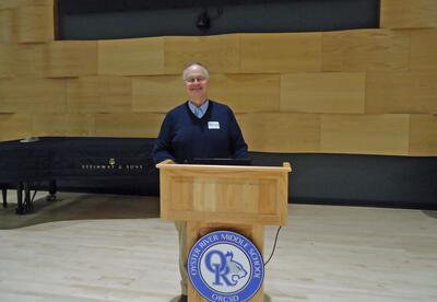 Dr. Matt Davis stands at the podium in the ORMS concert hall during his Science Friday presentation.