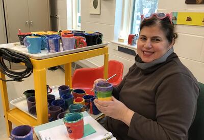 Teacher holding handmade clay mugs