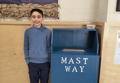Boy in blue standing beside homemade mailbox