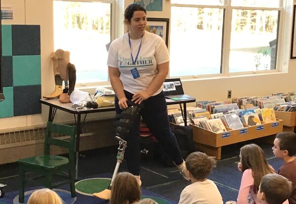 Woman demonstrating the use of a prosthetic leg to a room of students