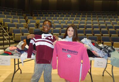 Two students hold up shirts they found during the clothing swap in the ORMS concert hall pose