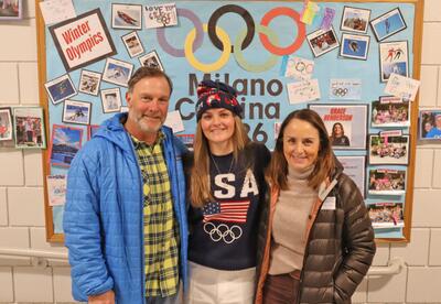 Grace and her parents stand in front of Olympic-themed artwork at Moharimet school.