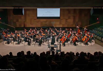 Music Teacher Andrea von Oeyen conducts string students during the orchestra concert.