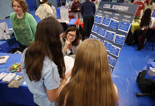 Students are seen engaging in conversation with a college representative during the fair.