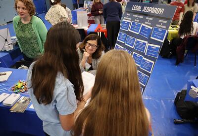 Students are seen engaging in conversation with a college representative during the fair.