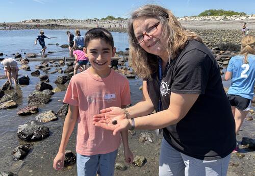 Teacher and boy student displaying a hermit crab while on the beach