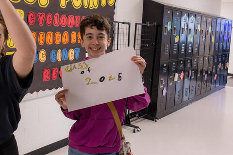 An SBEP student smiles holds up a sign that reads "class of 2025."