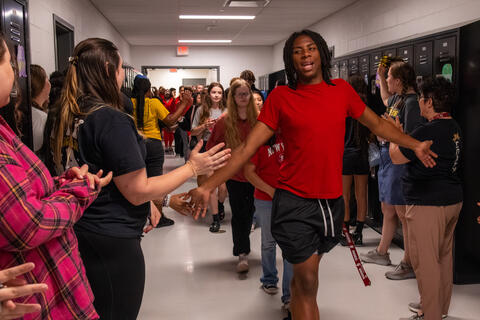 An SBEP senior student high fives students and teachers as he walks by. 