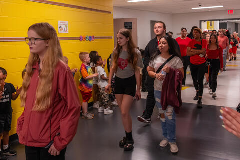 SBEP senior students walk together down a hallway as elementary students applaud for them. 