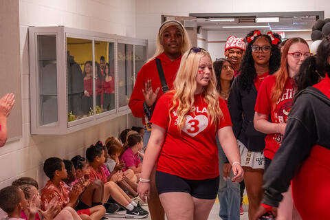 An SBEP senior student waves as she walks past applauding elementary kids. 