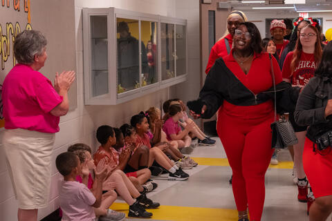 An SBEP senior smiles at applauding elementary students as she walks by. 
