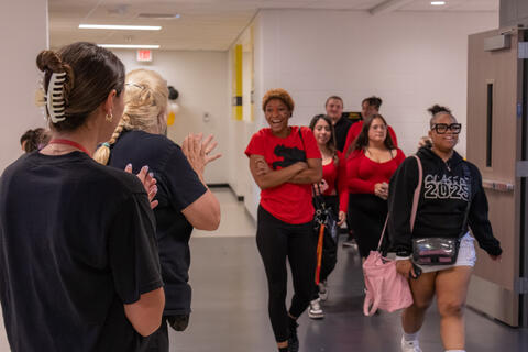 Elementary school teachers applaud the class of 2025 as they walk past them. 