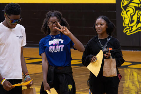 An eighth-grade student holds up a peace sign for a photo. 