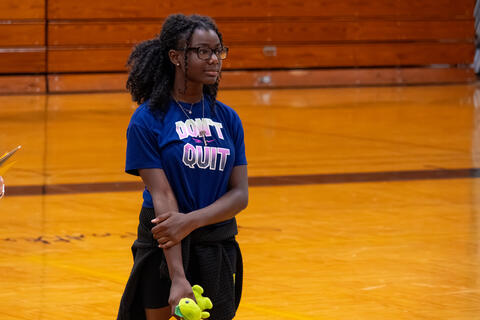 An eighth-grade student holds her right arm and looks off-camera. 