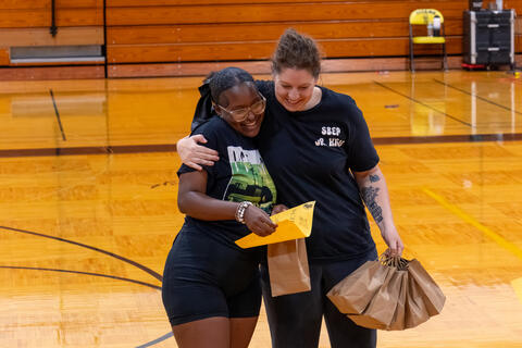 A teacher and an eighth-grade student hug each other. 