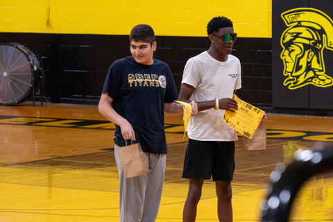 Two eighth-grade students stand beside each other while holding award certificates. 