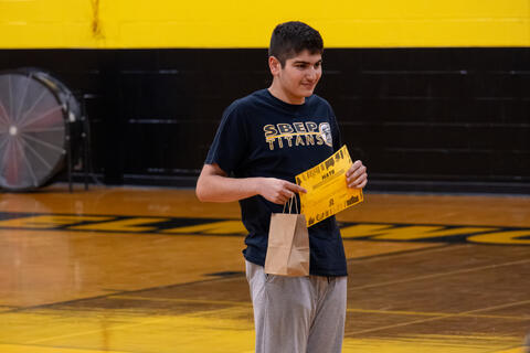 An eighth-grade student smiles and poses while holding his award certificate. 