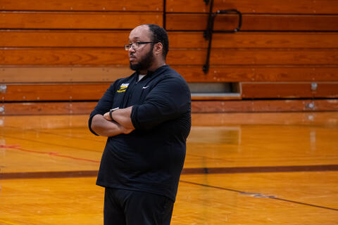 An SBEP paraprofessional stands with his arms crossed. 