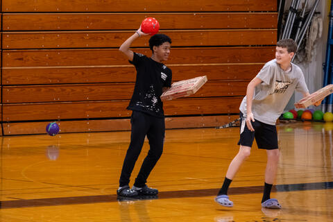 An eighth-grader chases another student with a dodgeball during a game. 