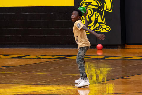 An eighth-grade student winds up to throw a dodgeball during a game. 