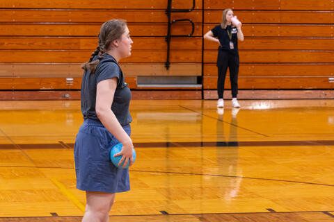 A teacher stands as she participates in a game of dodgeball. 