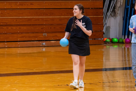 A teacher smiles while walking across the gym floor. 
