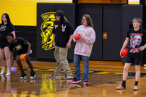 A group of eighth-grade students stand together, prepared to play dodgeball. 