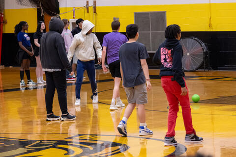 Several eighth-grade students crowd together during a game of dodgeball. 
