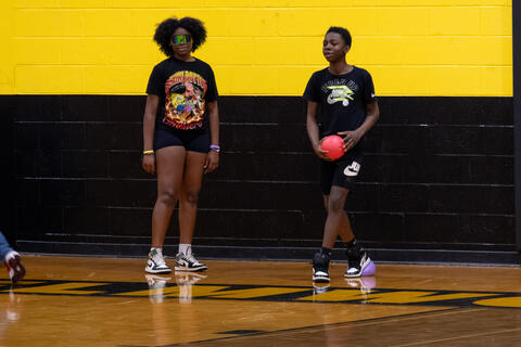 Two eighth-grade students stand beside each other during a game of basketball. 