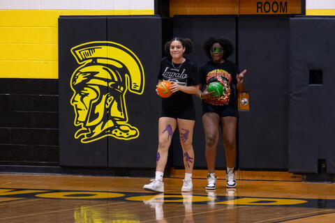 Two eighth-grade students stand together during a game of dodgeball. 
