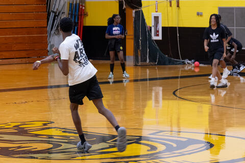 An eighth-grade student throws a dodgeball during a game. 